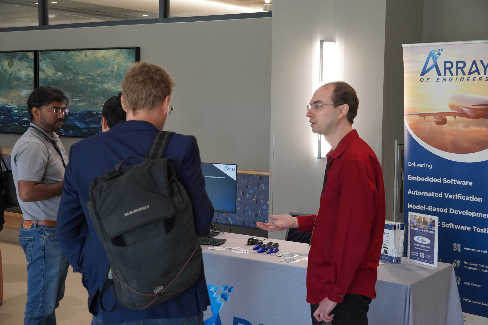 A representative at the Array booth speaks with attendees during an event, showcasing software and development services